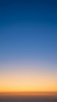 Stunning sunset sky gradient transitioning from deep blue to warm orange and yellow hues creating peaceful atmospheric background for design projects.