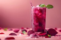 Fresh beetroot juice cocktail with ice cubes, mint leaves and striped straw in tall glass on pink background, surrounded by sliced beets. Refreshing summer drink.