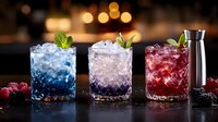 Colorful cocktails with crushed ice, fresh berries and mint garnish arranged on dark bar counter with bokeh lights background. Refreshing summer drinks.