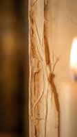 Weathered stone column with natural cracks and erosion patterns in warm sunlight creating architectural texture and ancient building detail.