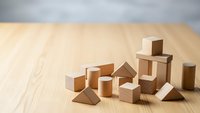 Wooden geometric blocks arranged on light wood surface creating minimalist composition for educational toys, building concepts, and creative play activities.