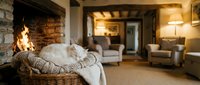 Cozy rustic living room interior with wicker basket, knitted blankets, stone fireplace and comfortable seating for home decor and lifestyle concepts.