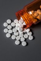 White pharmaceutical pills spilling from amber prescription bottle on dark background, dramatic lighting highlights medical and healthcare concept.
