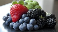 Fresh mixed berries including strawberry, blueberries and blackberries with mint leaves arranged on white plate for healthy eating and nutrition concepts.
