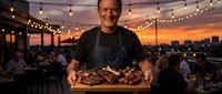 Smiling chef presenting grilled meat platter on rooftop restaurant terrace with string lights and sunset city skyline background during evening service.