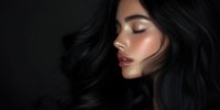 Young Asian woman with glowing skin and flowing black hair against dark background, side profile view showcasing natural makeup and closed eyes in dramatic lighting.