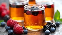 Fresh berries and honey in glass jar on wooden table, natural organic ingredients for healthy breakfast and dessert recipes. Selective focus on foreground.
