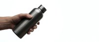 Man's hand holding black insulated water bottle on white background, isolated for product mockup and promotional design use.