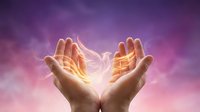 Cupped hands releasing glowing golden light energy against purple pink sky background, spirituality and healing concept.