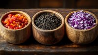 Three wooden bowls filled with diced red bell peppers, black sesame seeds, and chopped purple onions arranged on rustic wood surface for cooking preparation.