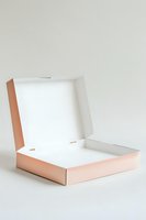 Empty open rose gold cardboard box with white interior on light background, minimalist packaging mockup for product presentation and branding design.