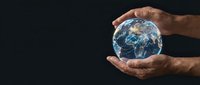 Male hands gently protecting planet Earth globe against dark background symbolizing environmental care, conservation and global responsibility.