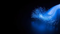 Blue fiber optic cables with glowing light particles on dark background for technology and communication concepts.