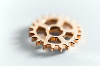 Single bronze metallic cogwheel on white background with shallow depth of field, mechanical part close up view for industrial and engineering concepts.