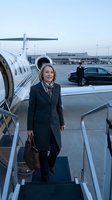 Mature woman in business attire boarding private jet at airport tarmac, holding leather briefcase, professional travel and executive lifestyle concept.