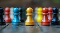 Colorful wooden chess pawns in blue, yellow and red standing on board with blurred pieces in background. Strategic game concept for business planning.
