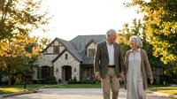 Senior couple walking hand in hand in front of suburban home during golden hour sunset, retirement lifestyle and real estate concept.