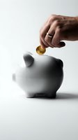 Male hand inserting golden coin into white ceramic piggy bank on neutral background representing savings, investment and financial planning concepts.