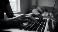 Professional hands typing on laptop keyboard in modern office workspace for business productivity and remote work applications.