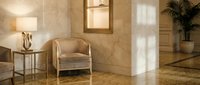 Elegant beige armchair in luxurious marble interior with golden accents and soft lighting creating sophisticated hotel lobby or upscale residential space.
