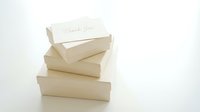 Stack of beige gift boxes with a handwritten thank you card on top, elegant minimalist style on white background.