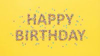 Happy Birthday text made of colorful sprinkles on bright yellow background with scattered confetti, festive celebration greeting card concept.