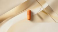 Orange capsule pill on neutral beige background with soft geometric shadows for healthcare and pharmaceutical design concepts.