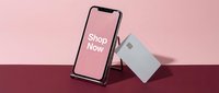 Smartphone with shop now screen and credit card on pink and burgundy background, online shopping and mobile payment concept.