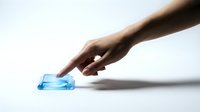 Male hand with dark skin tone reaching toward blue glass or acrylic block on white surface, conveying concepts of choice, selection, decision-making, and business strategy for corporate presentations.