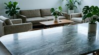 Modern living room interior with marble table, beige sectional sofa, houseplants and minimalist decor for contemporary home design and furniture.