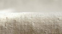 Natural beige linen fabric texture with visible fibers and weave pattern. Organic textile material background for crafting and sewing projects.