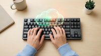 Professional workspace with hands typing on modern mechanical keyboard featuring colorful RGB backlighting for gaming and productivity tasks.