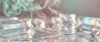 Abstract smoke swirls over iridescent crystal surface with rainbow reflections and bokeh lights creating dreamy ethereal atmosphere for luxury design.