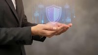 Businessman holding glowing shield icon with digital buildings, representing cybersecurity, data protection, and network security solutions for enterprise systems.