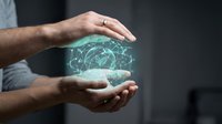 Male hands protecting glowing digital brain network with neural connections representing artificial intelligence, machine learning and cognitive technology innovation.