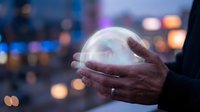 Man holding glowing crystal ball with blurred city lights in background at dusk, symbolizing fortune telling, future prediction, and mystical divination practices.