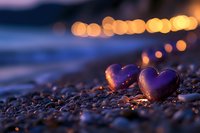 Heart-shaped stone on beach pebbles at sunset with warm bokeh lights creating romantic atmosphere for love and relationship concepts.