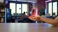 Businessman holding holographic brain projection in modern office workspace with colleagues working in background.