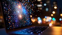 Laptop screen displaying colorful sparkle effect against blurred city lights background, creating magical digital transformation atmosphere with bokeh glow.