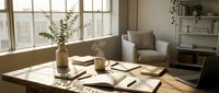 Bright workspace with wooden desk, open notebooks, coffee cups, and potted plants near large windows with natural sunlight, suitable for business, education, and lifestyle content.