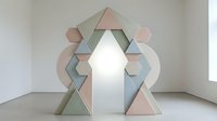 Geometric arrow pointing upward composed of pastel pink, sage green, and gray triangular shapes arranged symmetrically on white floor in minimalist interior space.