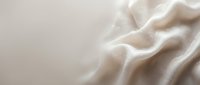 Soft cream fabric with elegant flowing folds and gentle waves creating luxurious textile background for fashion and interior design projects.
