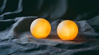 Glowing orange spherical lights on dark textured fabric create mysterious atmospheric mood. Decorative elements for interior design and festive decoration.