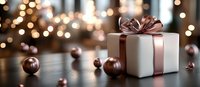 Elegant white gift box with rose gold ribbon and bow on dark wooden surface with scattered metallic spheres and festive bokeh lights in background.