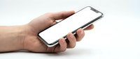 Hand holding modern smartphone with blank white screen mockup for app presentation and mobile interface design on clean background.
