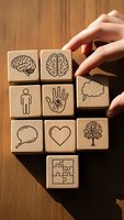 Wooden blocks with mental health and psychology symbols protected by caring hands on warm wood surface for wellness and mindfulness concepts.