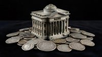 Classical bank building with columns surrounded by silver coins on dark background representing financial institution and monetary system.