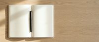 Open notebook with blank pages and black pen on wooden surface, ready for writing, planning, or note-taking.