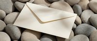 Elegant cream envelope resting on smooth river stones creating peaceful zen composition for correspondence, stationery, and communication designs.