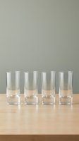 Four empty clear glass tumblers arranged in row on wooden table against neutral gray background for kitchen and dining concepts.